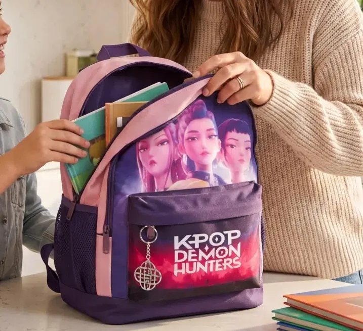 Un classeur et des cahiers glissés dans le compartiment principal du sac, poche latérale en filet et porte-clé visibles.